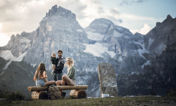 Familie sitzt auf Bank mit Berg im Hintergrund