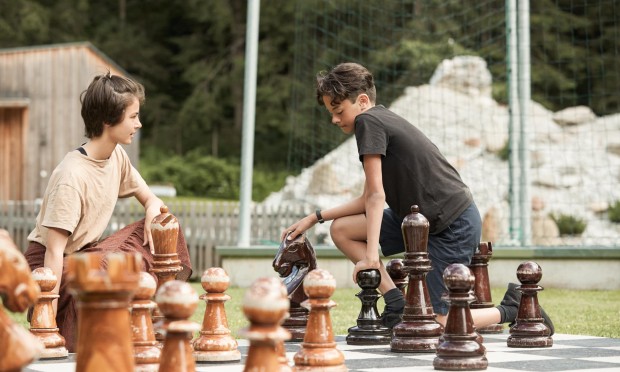 2 Teenager spielen Schach mit großen Figuren im freien