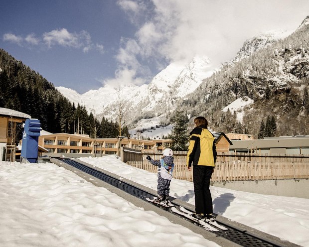 Erste Skiversuche im Garten vom Familienhotel Feuerstein, dem idealen Ort für einen Familienurlaub in den Bergen