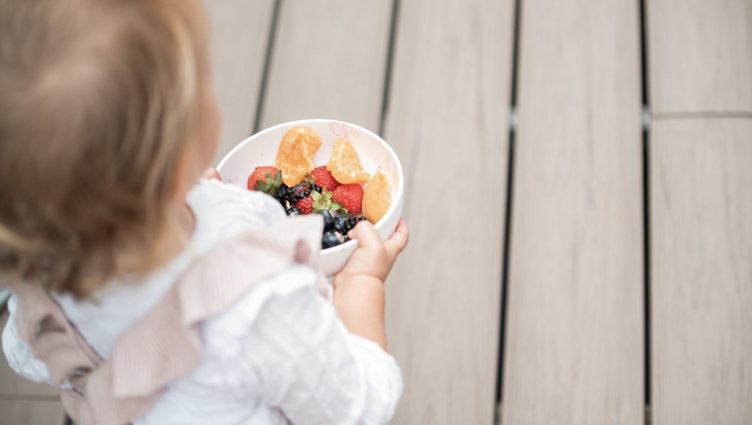 Kleines Kind hält eine Schüssel mit Obst