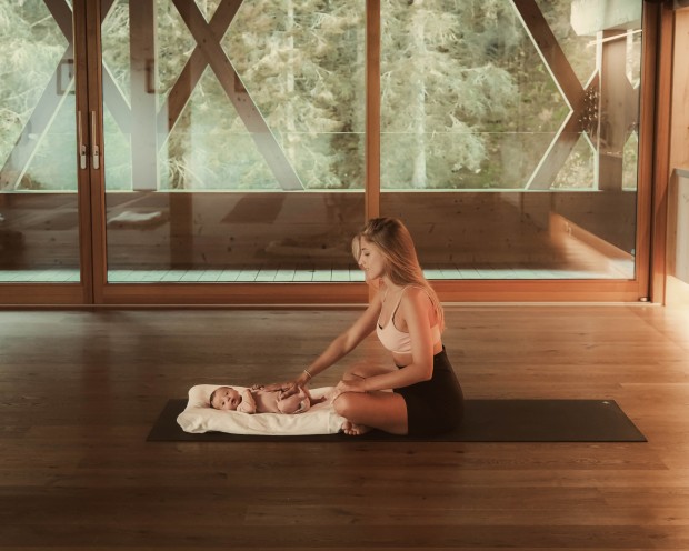 Mutter sitzt mit Baby im Yoga Raum