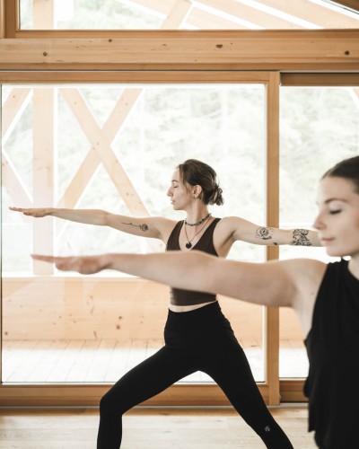 2 Frauen machen Yoga Übungen im Stehen im Yoga Raum