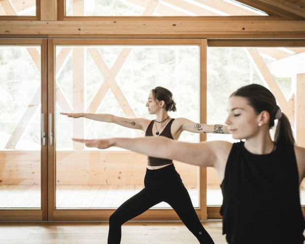 2 Frauen machen Yoga Übungen im Stehen im Yoga Raum