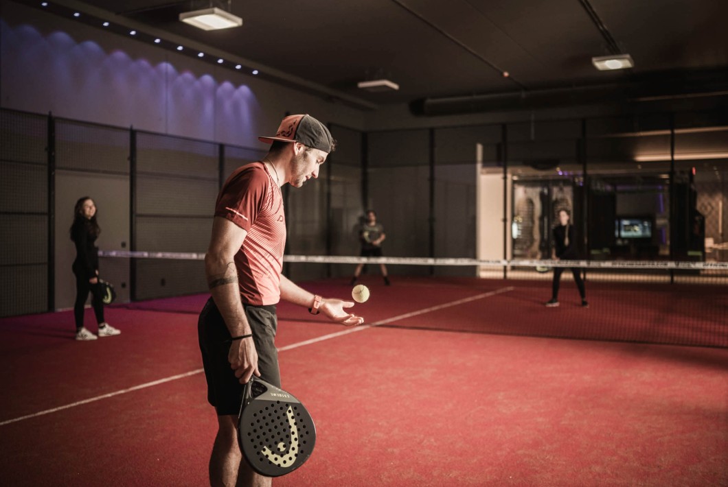 Mann spielt Paddel mit Partnerin gegen ein anderes Team