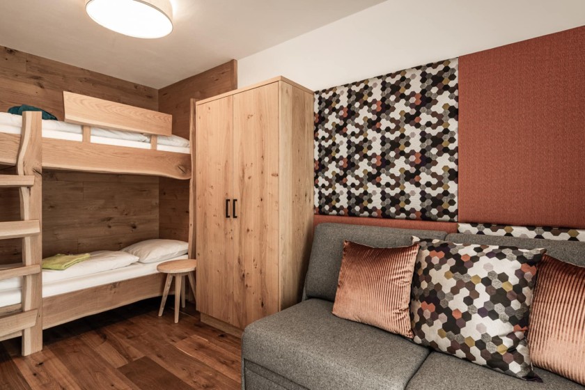 Stockbett mit Holzleiter, Kleiderschrank und Couch