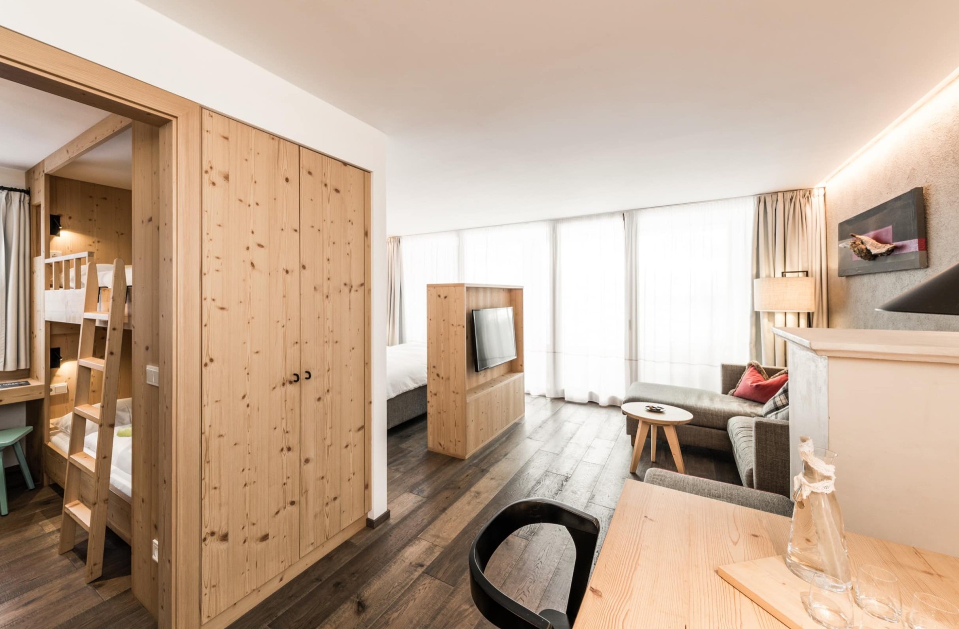 Zimmer mit Fernseher, Esstisch und Stockbett in einen anderen Raum