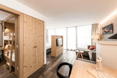 Zimmer mit Fernseher, Esstisch und Stockbett in einen anderen Raum